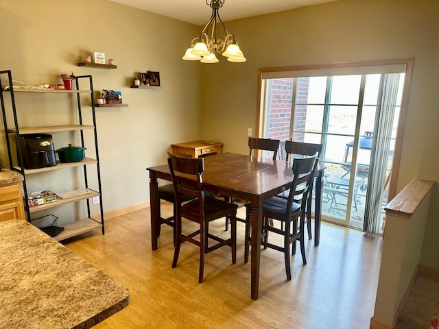 dining room featuring baseboards, a notable chandelier, and light wood-style flooring