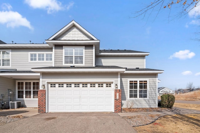 view of front of property featuring aphalt driveway, cooling unit, an attached garage, and brick siding