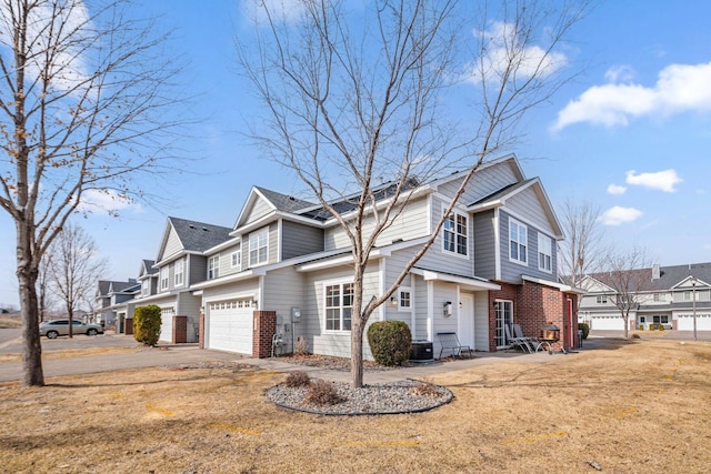 view of property exterior featuring cooling unit, driveway, an attached garage, brick siding, and a residential view