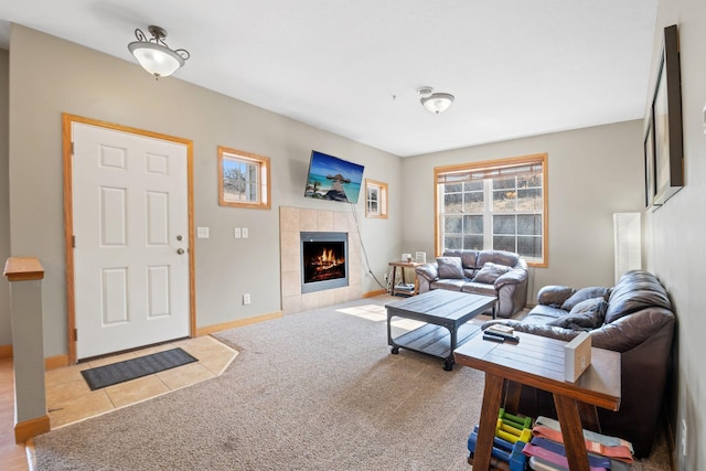 living area featuring a tiled fireplace, baseboards, and carpet