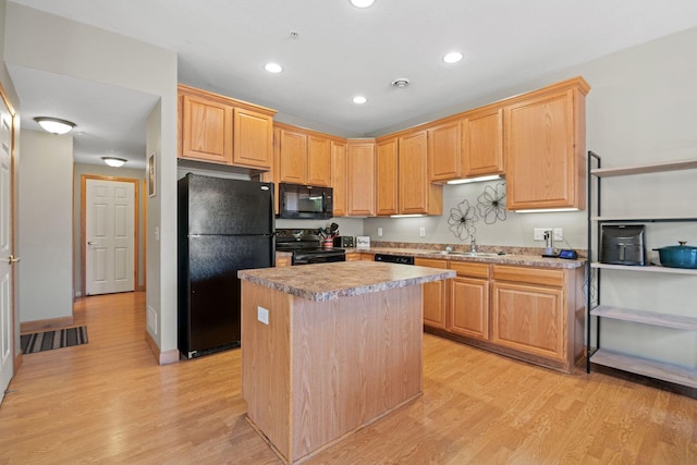 kitchen featuring black appliances, light countertops, light wood finished floors, and a center island