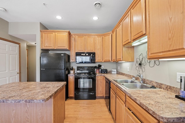 kitchen with light wood-type flooring, black appliances, light brown cabinetry, a sink, and light countertops