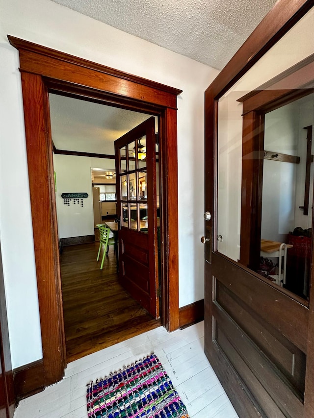 corridor featuring baseboards, a textured ceiling, and hardwood / wood-style floors