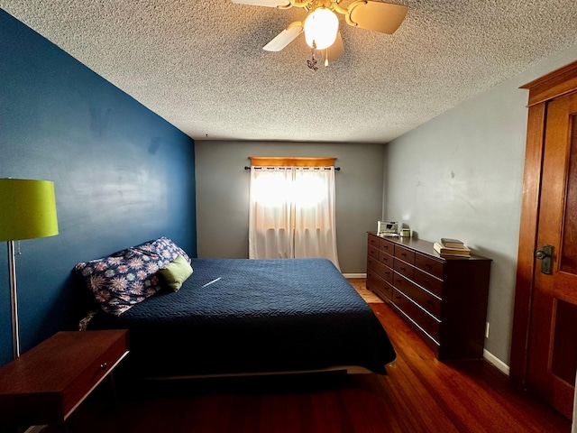 bedroom with wood finished floors, baseboards, and a textured ceiling