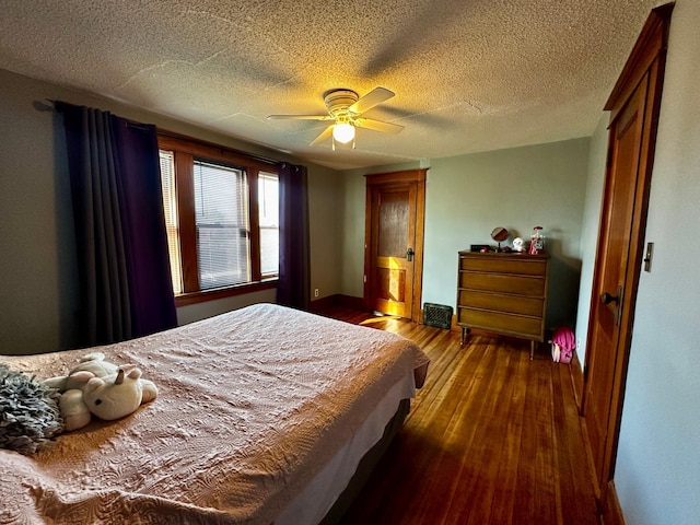 bedroom featuring baseboards, dark wood-type flooring, ceiling fan, and a textured ceiling