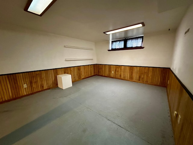 unfurnished room with wainscoting, concrete floors, and wood walls