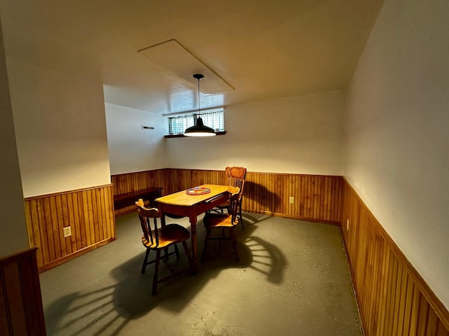 dining space with visible vents, wainscoting, concrete flooring, and wood walls