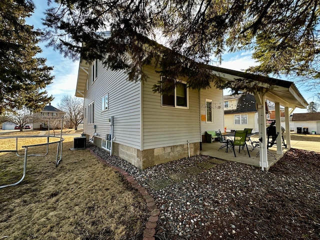 view of side of property with central air condition unit and a patio area