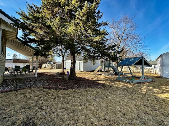 view of yard with an outdoor structure, a playground, a patio, and fence