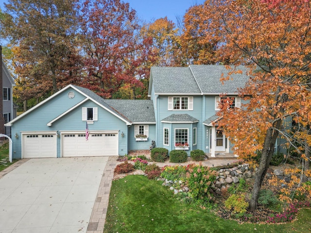 traditional-style house featuring driveway, a shingled roof, and a garage