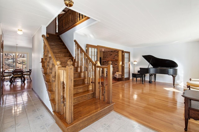 staircase featuring french doors, baseboards, an inviting chandelier, and wood finished floors