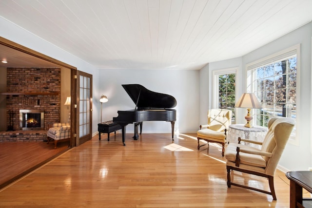 sitting room with light wood-style flooring, french doors, wooden ceiling, a fireplace, and baseboards