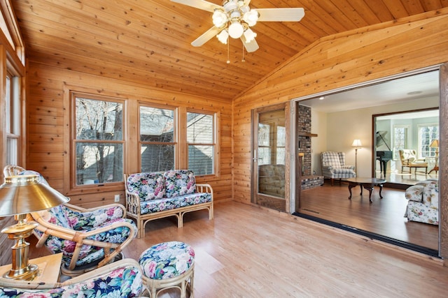 interior space featuring wooden walls, a ceiling fan, wood finished floors, lofted ceiling, and wood ceiling