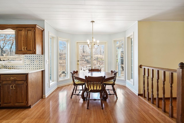 dining space with baseboards, a notable chandelier, and light wood finished floors