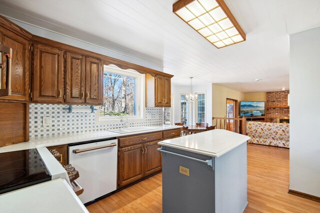 kitchen featuring light wood-style flooring, a sink, a center island, white dishwasher, and light countertops