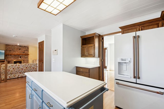 kitchen with open floor plan, light wood-type flooring, light countertops, a fireplace, and white refrigerator with ice dispenser