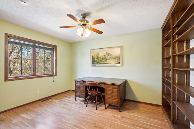 home office with ceiling fan, baseboards, a textured ceiling, and light wood-style flooring