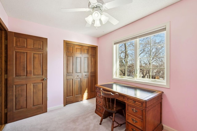 office featuring a ceiling fan, light colored carpet, and baseboards