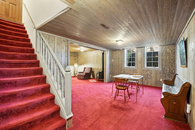 interior space featuring carpet, wooden ceiling, and wooden walls