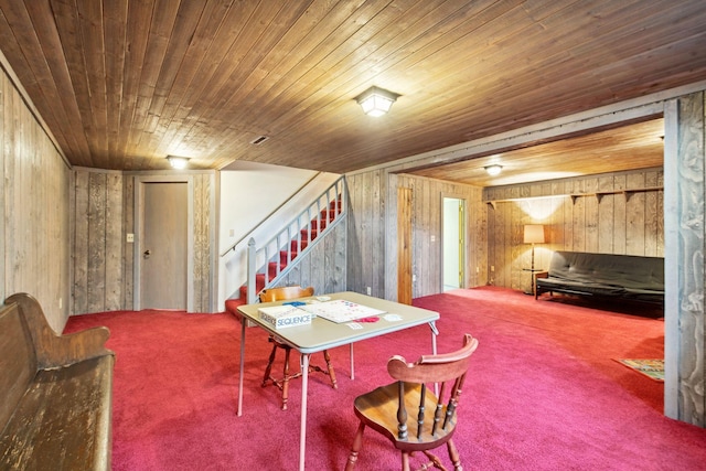 carpeted dining area featuring stairs, wooden walls, and wood ceiling