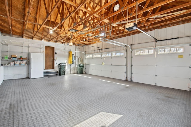 garage featuring a garage door opener and freestanding refrigerator