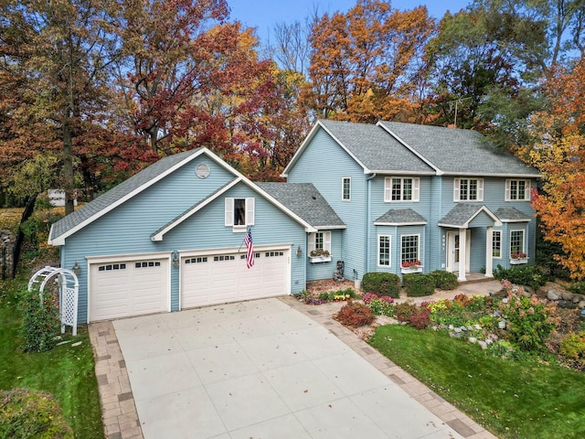 traditional home featuring an attached garage, driveway, and roof with shingles