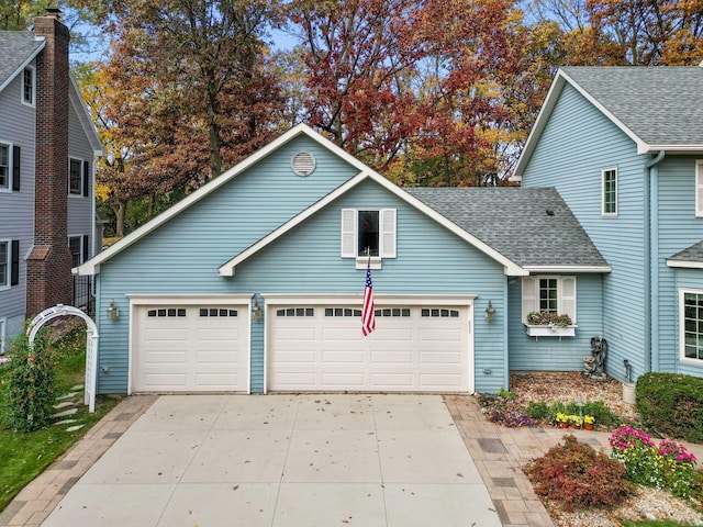 view of front of house featuring an attached garage, driveway, and roof with shingles