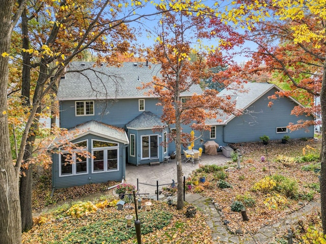 rear view of property with a patio area and a shingled roof