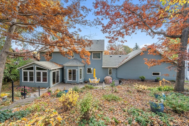 rear view of property featuring a patio, roof with shingles, and a sunroom