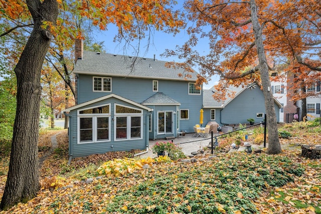 rear view of property with a patio area, a chimney, a shingled roof, and fence