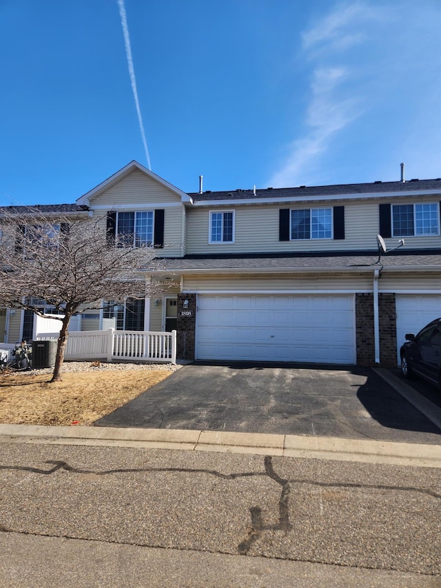 townhome / multi-family property with aphalt driveway, an attached garage, and brick siding