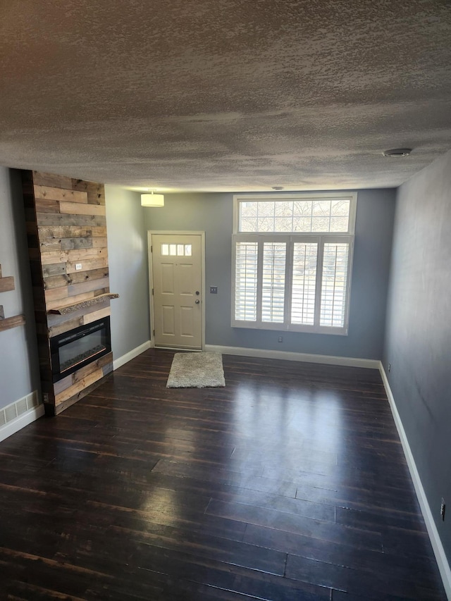 entrance foyer featuring baseboards, a textured ceiling, dark wood finished floors, and a fireplace