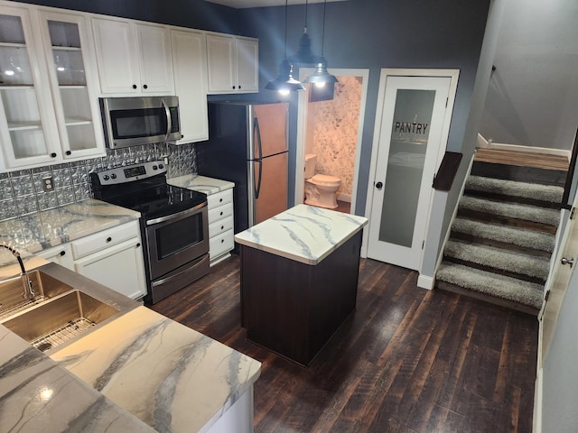 kitchen featuring dark wood-type flooring, decorative backsplash, white cabinetry, stainless steel appliances, and glass insert cabinets