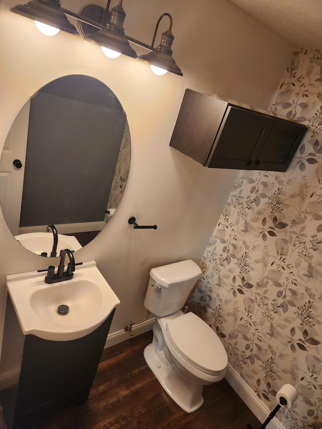 bathroom with toilet, vanity, baseboards, and wood finished floors