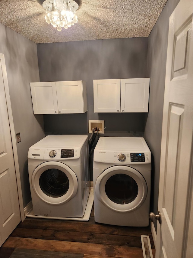 laundry area featuring independent washer and dryer, a textured ceiling, dark wood-style floors, cabinet space, and a chandelier