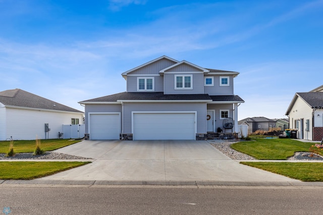 view of front of house with a front yard, concrete driveway, fence, and stone siding