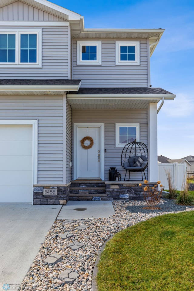 view of front of house with entry steps, fence, a garage, and a shingled roof