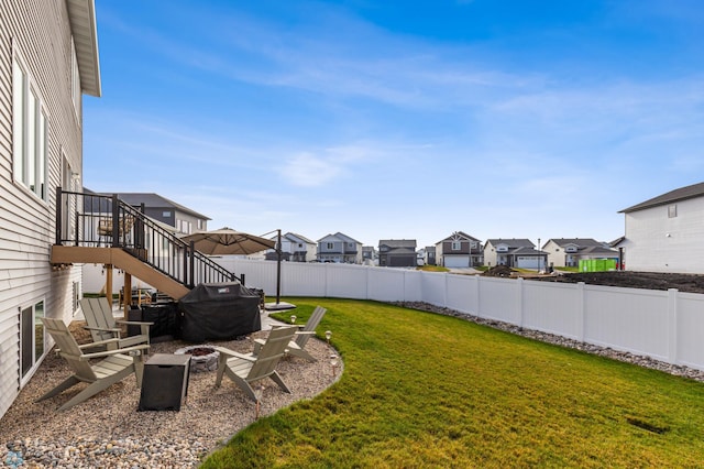 view of yard with stairway, a residential view, a fenced backyard, and an outdoor fire pit