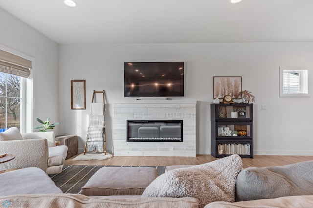 living area featuring recessed lighting, baseboards, wood finished floors, and a glass covered fireplace