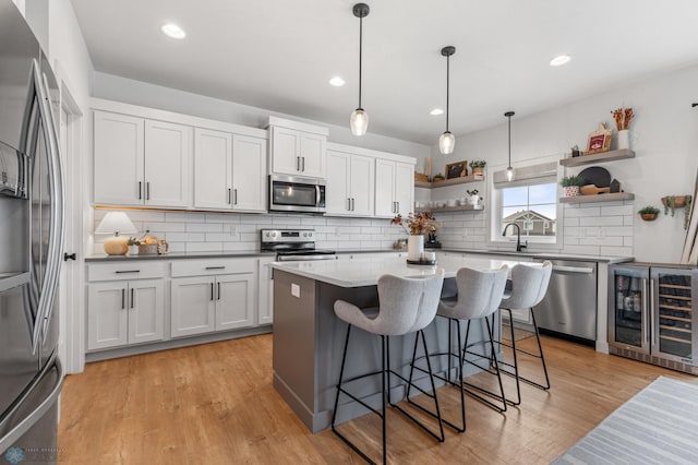 kitchen with light wood finished floors, wine cooler, a kitchen breakfast bar, stainless steel appliances, and open shelves