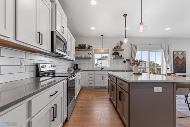 kitchen with open shelves, a kitchen breakfast bar, tasteful backsplash, a center island, and stainless steel appliances