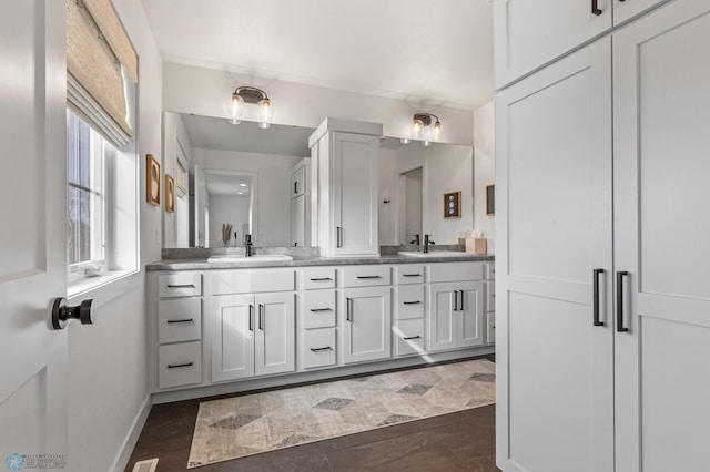 full bath with double vanity, baseboards, and a sink