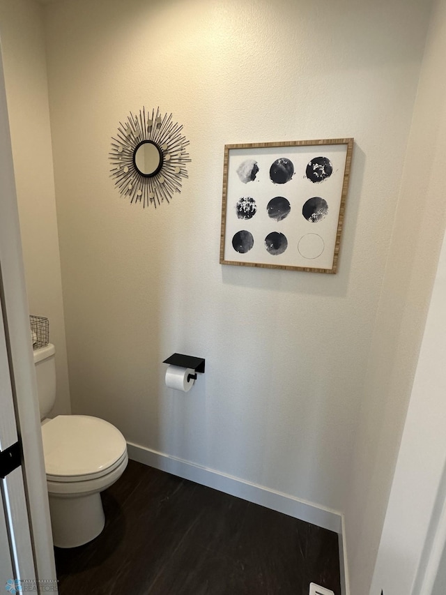 bathroom featuring toilet, wood finished floors, and baseboards