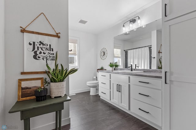 full bath featuring vanity, toilet, baseboards, and visible vents