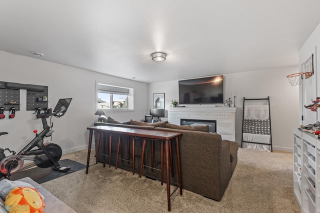 living room with a brick fireplace, baseboards, and carpet