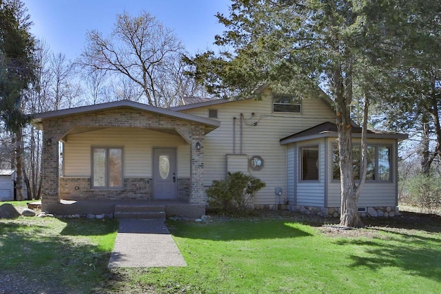 bungalow-style house featuring brick siding, a sunroom, and a front yard