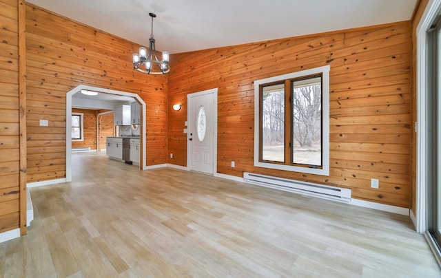 foyer with light wood-style floors, arched walkways, a baseboard radiator, and wooden walls