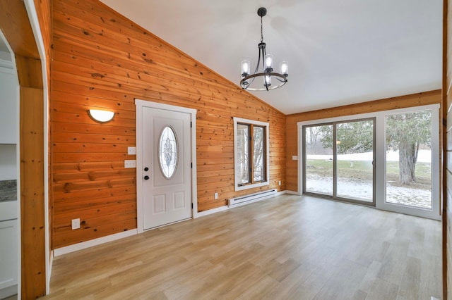entryway featuring an inviting chandelier, high vaulted ceiling, wood walls, light wood-type flooring, and a baseboard heating unit