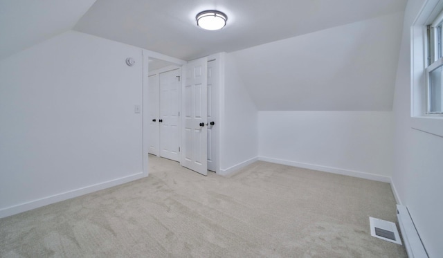 additional living space with carpet floors, visible vents, baseboards, and lofted ceiling