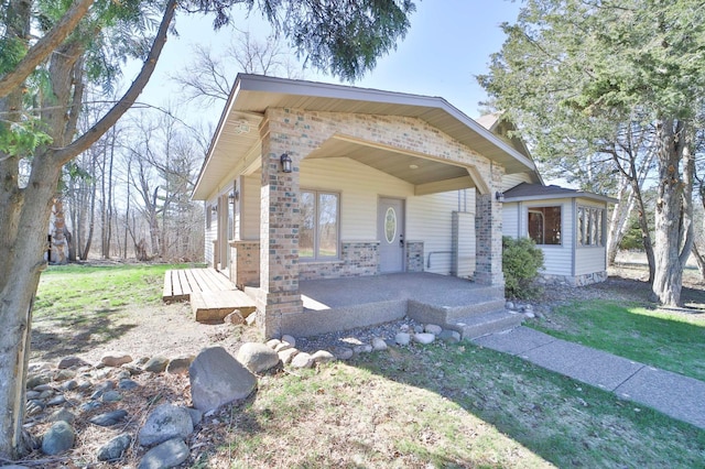 bungalow featuring a front yard, a porch, and brick siding